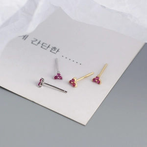 Macro detail of gold and silver four-leaf clover stud earrings with pink zircon stones