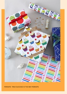 Close-up of birthday gift wrapping paper with cake and balloon patterns and gold ribbons