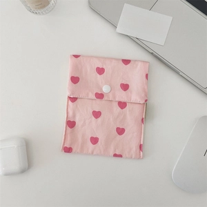 Detail of pink canvas pouch with red heart patterns and white snap button closure