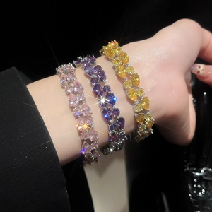 Macro shot of silver bracelets featuring heart-shaped pink, purple, and yellow gemstones