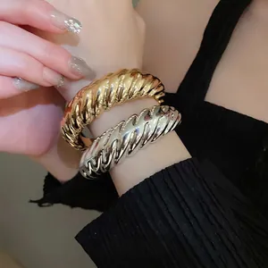 Modern twisted metal cuff bracelets in gold and silver finish with spiral design