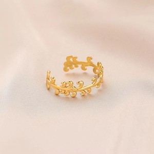 Close-up of golden vine leaf open ring on soft pink silk background with detailed texture