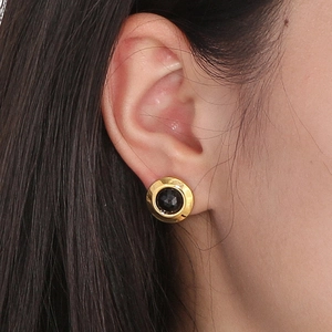 Macro detail of vintage black crystal earring with faceted cut and golden metal rim