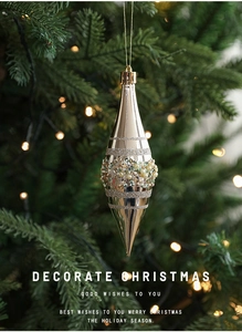 Champagne gold Christmas ornament with sequins and pearls hanging on a festive tree branch