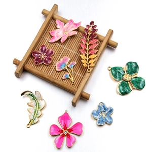 Macro detail of enamel flower and leaf charms in colorful metal for jewelry making