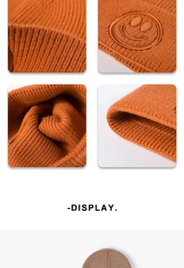 Close-up of caramel orange knit beanie with smiley face embroidery and thick texture