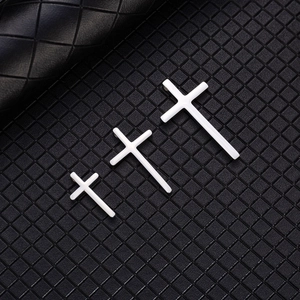 Three sizes of polished white cross pendants displayed on black quilted leather texture