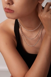 Detailed layered look of three silver chains featuring small pearls and snake bone design