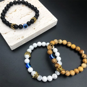 Detail of beaded crown bracelets with natural stones and evil eye charms on a stone base