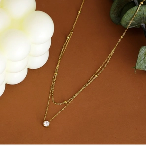Detail view of double layer gold necklace with beads and a sparkling zircon stone