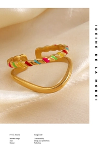 Detail of gold twisted rope ring with colorful enamel inlay on cream satin fabric