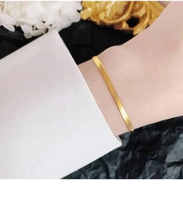 Close-up of elegant gold snake chain bracelet with textured scales on a woman wrist