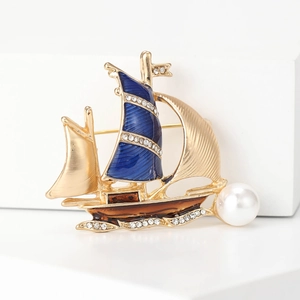 Elegant gold sailboat brooch with navy enamel, shimmering rhinestones, and white pearl accent
