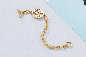 Close-up of golden Tree of Life charm and textured OT toggle clasp on metal bracelet