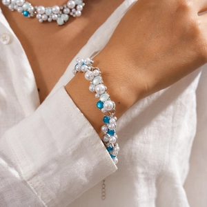 Detail view of multi-color resin beads and pearls necklace on a model with blue accents