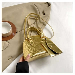Detail of metallic gold crocodile embossed shell bag with matching envelope mini pouch