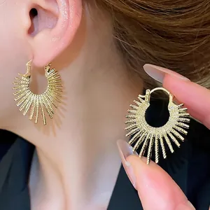 Fashionable gold sunburst hoop earrings with radiant spike design shown on ear