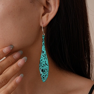Close-up of a bohemian teardrop earring in turquoise with black spots on a model