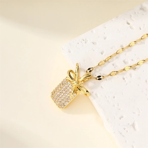 Elegant gold-plated bowknot pendant necklace with sparkling zircons on marble stand
