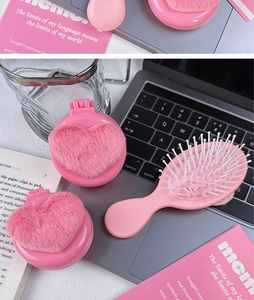 Close-up of heart-shaped plush folding hairbrush with mirror on desk setting