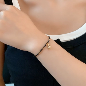 Detail of bohemian black bead bracelet with gold accents worn on a female wrist