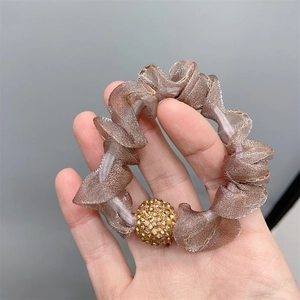 Close-up of brown mesh scrunchie featuring a sparkling rhinestone decorative ball detail