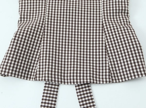Detailed view of brown and white gingham fabric with pleated hem and neat stitching