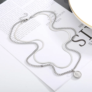 Macro detail of silver double-layered necklace with snake chain and coin portrait pendant