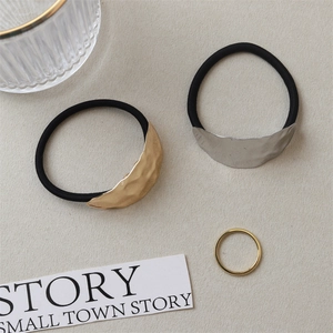 Close-up of textured gold and silver metal charms on black elastic hair ties