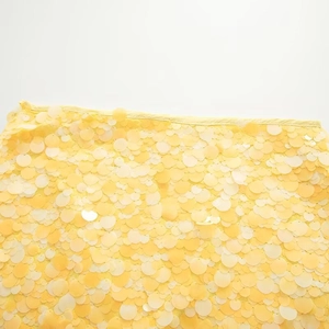 Close-up of yellow round sequin fabric detailing intricate sewing and texture