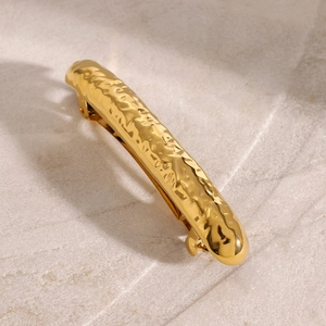 Close-up of golden hammered texture spring hair clip with polished metallic finish