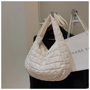 Detail of beige quilted puffer tote bag showing soft padded texture and large lattice pattern