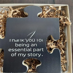 Detail of engraved black puzzle piece plaque in gift box with heartfelt thank you message