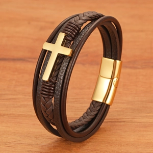 Brown multilayer leather cross bracelet with gold magnetic clasp on wooden surface