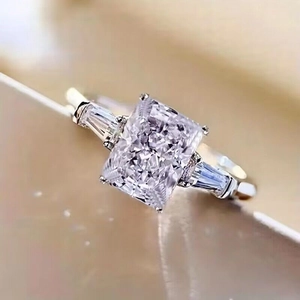 Macro shot of silver wedding ring with large rectangular center stone and side diamonds