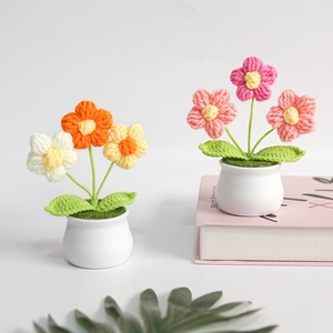 Handmade crocheted flower pot with colorful knitted blossoms in white ceramic base