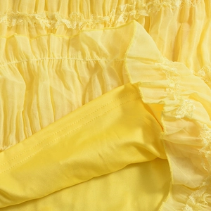 Macro shot of yellow pleated chiffon fabric with intricate lace trim and soft inner lining