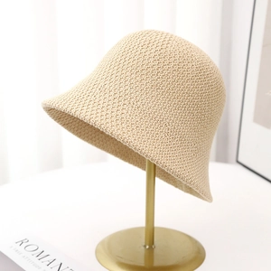 Close-up of beige woven bucket hat showing fine knit texture on a gold metal stand