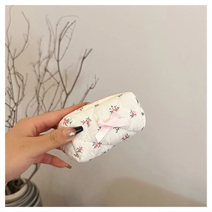 Detail of floral quilted cotton makeup bag with pink bow and zipper held in hand