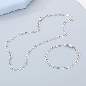 Macro shot of silver pig nose chain necklace and bracelet set on a minimal background