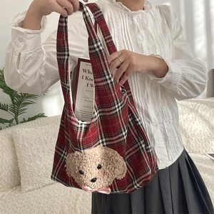 Detail of red plaid canvas tote bag featuring 3D plush puppy and pink satin bow