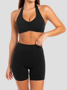 Front view of model wearing a black halter sports bra and high waisted fitness shorts set