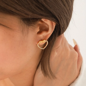 Elegant gold heart stud earrings with sparkling crystal pavé worn by a female model