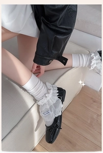 Close-up of white lace ruffle socks paired with black patent leather bow shoes