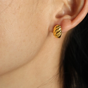 Gold croissant hoop earrings with ribbed texture worn by a model in a close-up view