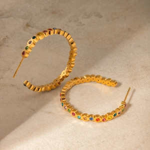 Détail de créoles en acier doré 18 carats ornées de zircons multicolores brillants