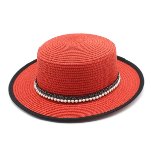 Classic red straw boater hat with black trim and pearl decorative band on white background