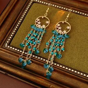 Détail de boucles d'oreilles vintage en or avec perles bleues sur fond vert