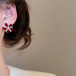 Detail of red flocked flower earring with zircon and pearl on a female model