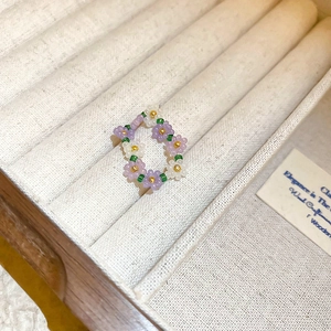 Macro shot of handcrafted purple and white floral beaded ring in a wooden box
